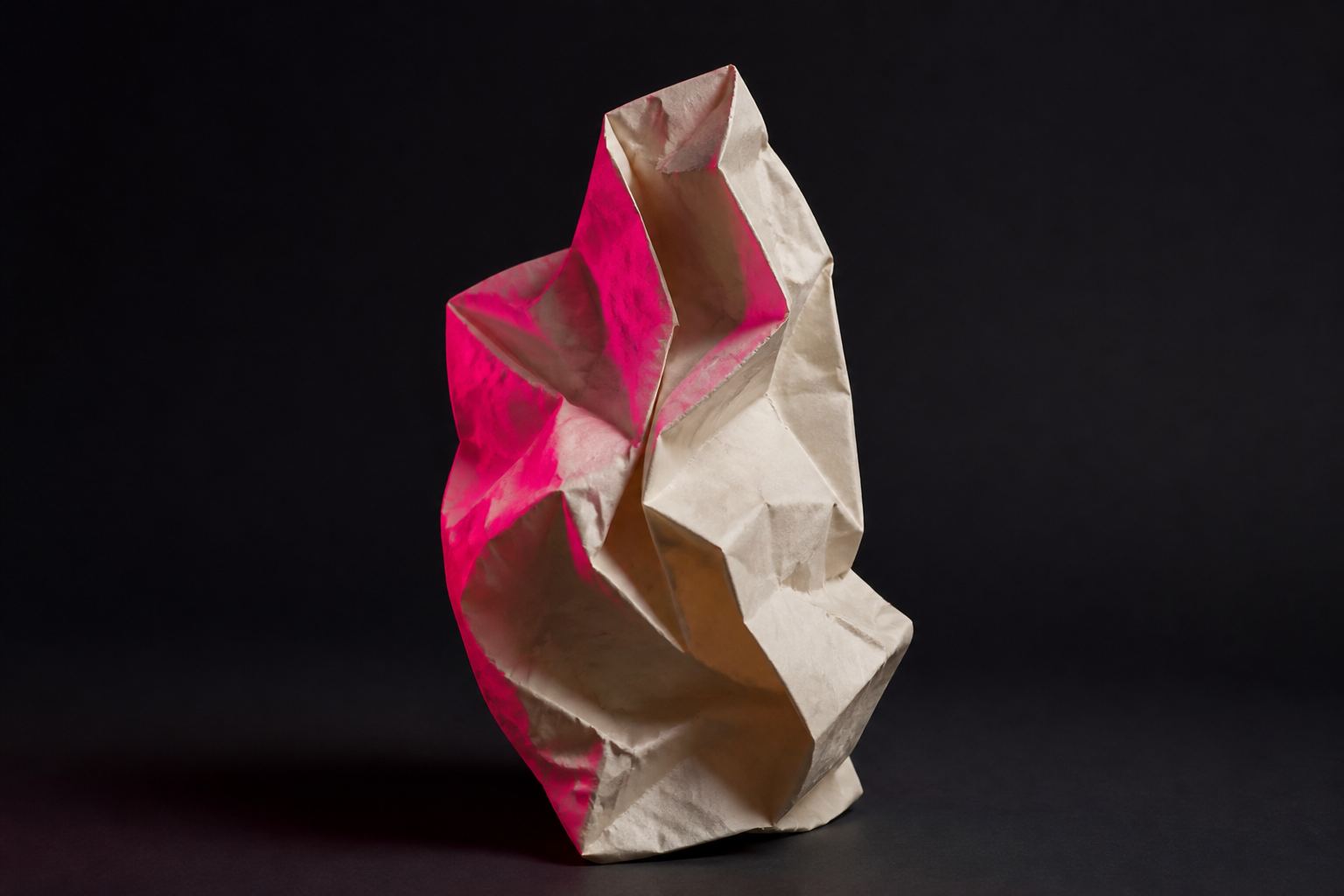 Crumpled cream paper sculpture with pink light on one edge