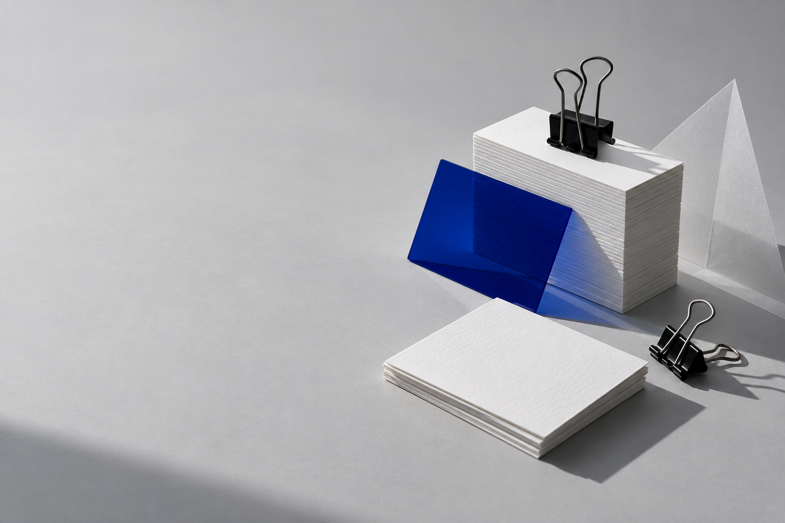 A stack of white note cards with one cobalt card and binder clips