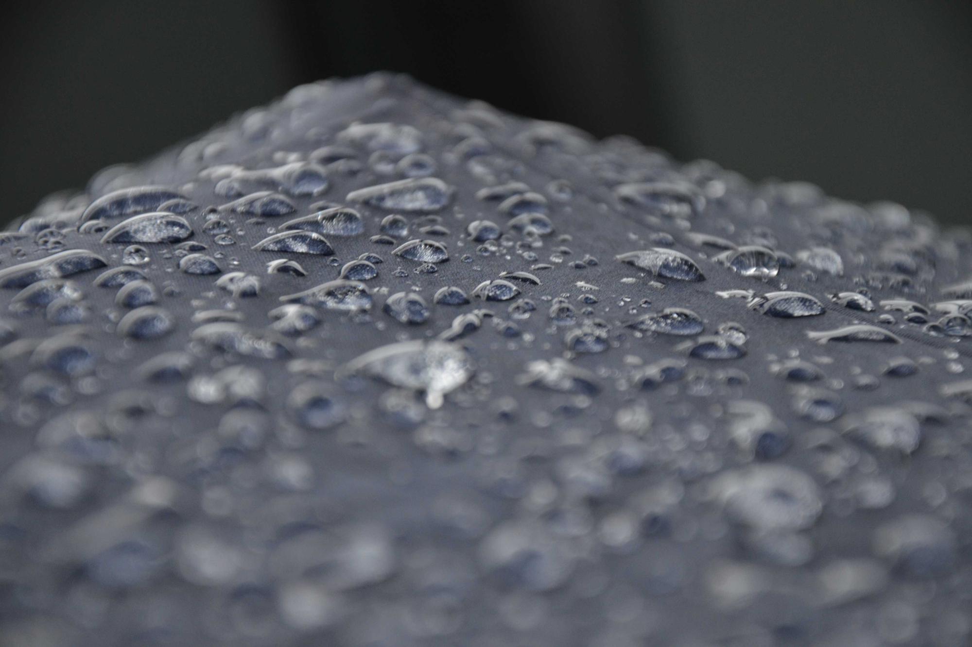 Water droplets beaded across a dark grey surface