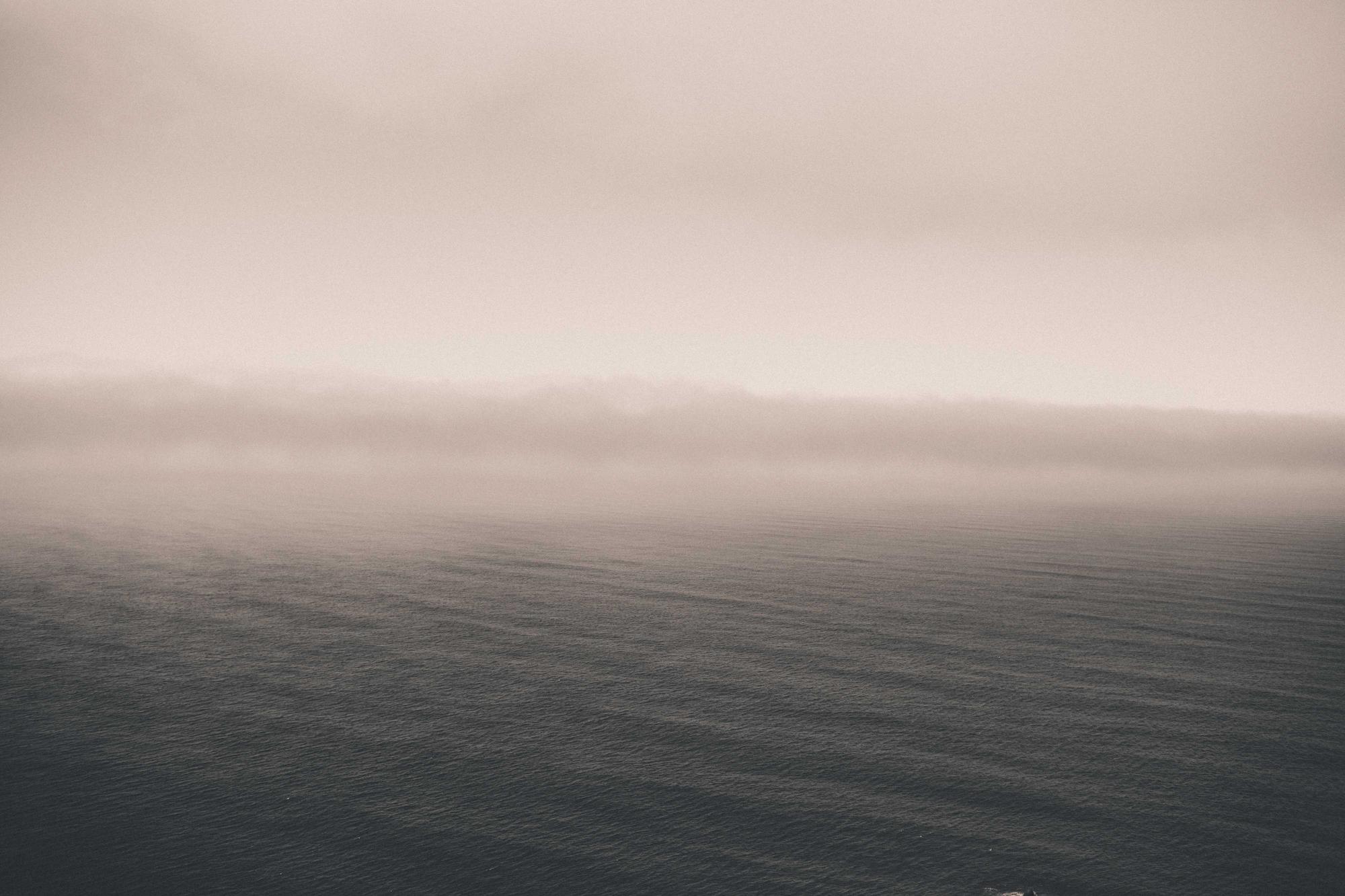 A calm grey sea meeting a soft pink sky