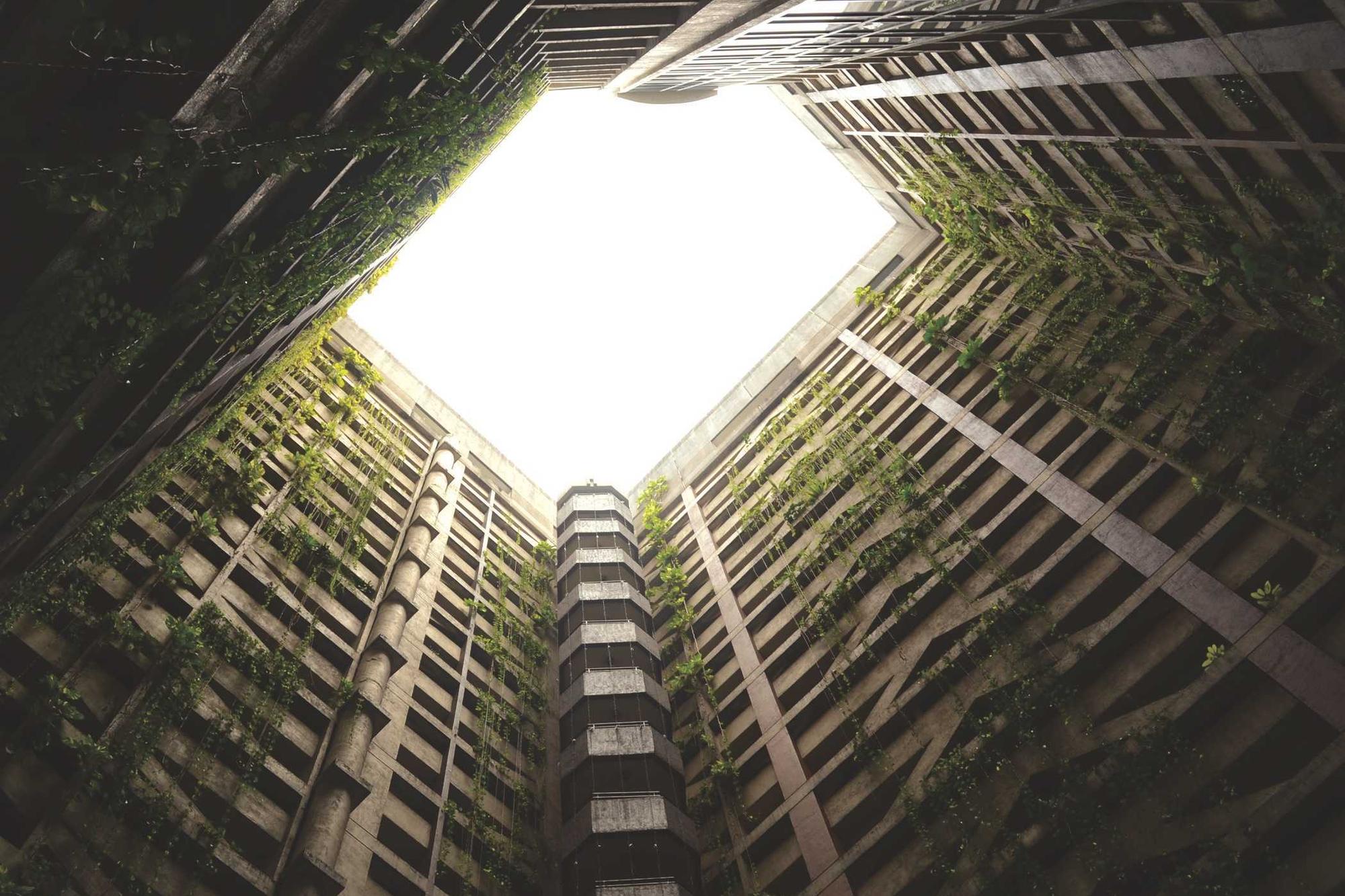 Looking straight up a tall building with a square of bright sky at the top